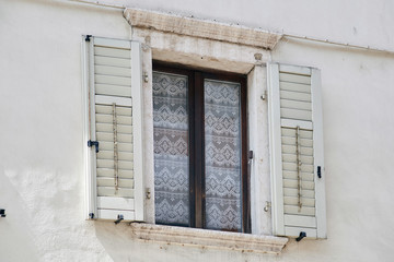 Italian window on the white wall facade with open wooden white color classic shutters