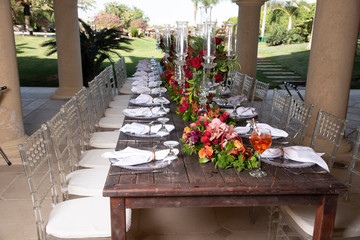 A beautifully decorated wooden table with flowers, dishes, glasses for a party or a wedding 