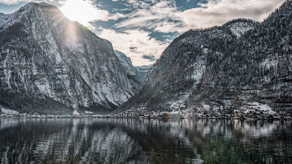 Fototapeta premium Snowy village Hallstatt at the foot of mountain with sun light in winter in Austria