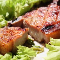 Juicy pork steak grilled on a plate on a fresh green salad