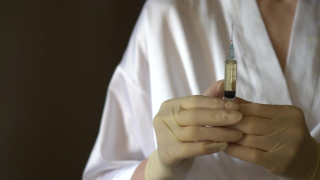 Self-injection of antibiotics. Female preparing needle for injecting her buttocks. Woman injecting buttocks.