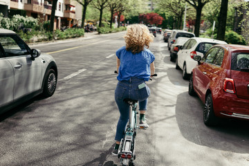 Girl on a bicycle on the background of the cityscape. Back view.