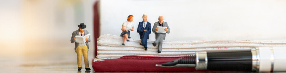Fototapeta premium Miniature people: Group of business team sitting on book with lamp idea using as background education or business cover page concept.
