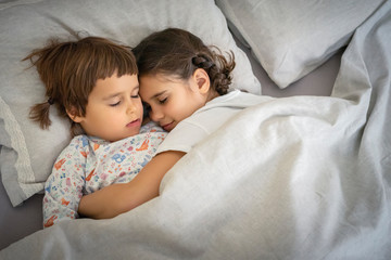 Two cute little sisters sleep together on the bed. Happy family while sleeping