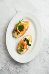 Hot bruschettas with salmon and vegetables on a plate