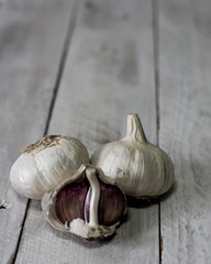 Bodegón de tres ajos blancos sobre tablero blanco y copyspace arriba