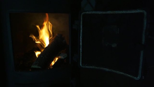 Fire in wood-burning stove with door closing