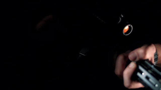 The modern AR-15 rifle with a collimator sight is highlighted in the dark. Close-up