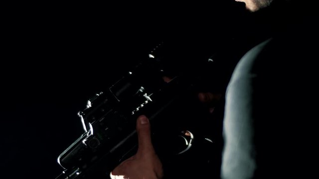 Special unit soldier throws a rifle into a combat position on a black background