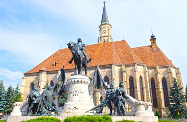 Fototapeta na wymiar The Matthias Corvinus Monument with the St. Michael's Church in the background, Union Square, Cluj Napoca, Romania
