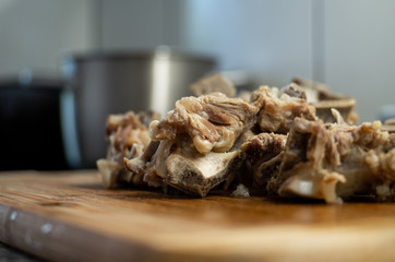 Cooked small pieces of veal bone with meat base for soup concentrate set of wood board in the kitchen