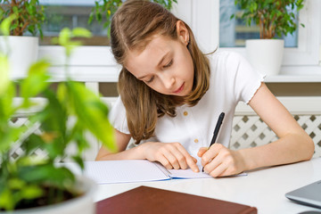 Schoolgirl doing her homework at home. Quarantine concept.