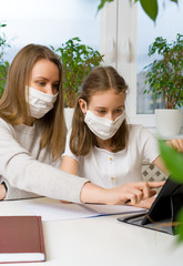 Schoolgirl with her mother at distance learning. Home schooling concept.