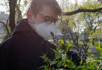 Young man in the park in n95 mask looking on flovers