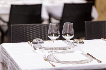 Two empty wineglasses on vacant restaurant table with selective focus on glasses and blurred soft focus background