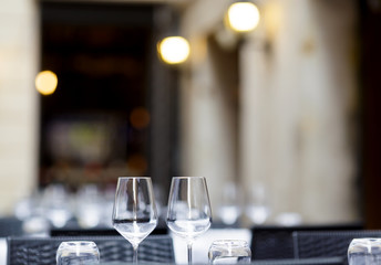 Two empty wineglasses on vacant restaurant table with selective focus on glasses and blurred soft focus background