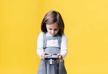 Girl using a photo camera on yellow background