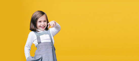 A girl points the finger on yellow background