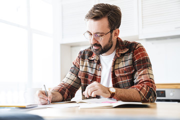 Portrait of young bearded man working with notes at home