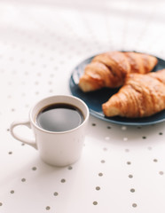 Coffee cup and fresh baked french croissants in blue plate on white background. Breakfast.