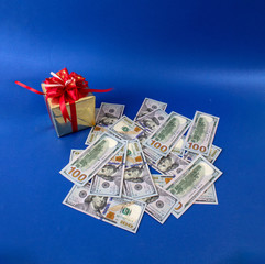 dollars along with a gift, a symbol of the crisis, venality, wealth, hoarding and poverty. Photo on a blue background