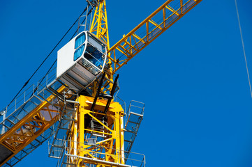 iron cabin of a yellow tower crane on a blue sky background close-up