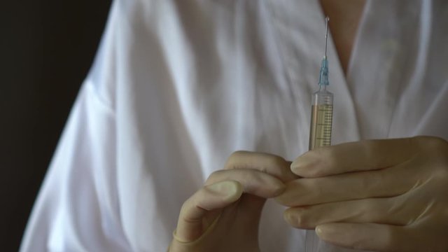 Self-injection of antibiotics. Female preparing needle for injecting her buttocks. Woman injecting buttocks.