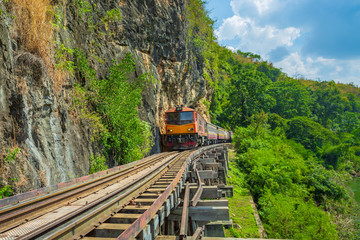 World war II historic railway, known as the Death Railway with a lot of tourists on the train taking photos of beautiful views over Kwai Noi River.