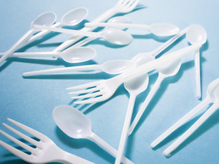 Plastic dishes, disposable tableware, plates, glasses, spoons, forks on a blue background. Caring...
