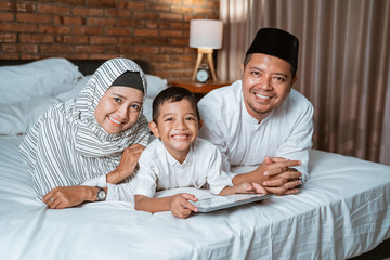 muslim family and son using tablet on the bed during bedtime