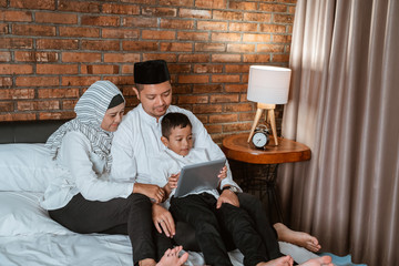 muslim family and son using tablet on the bed during bedtime