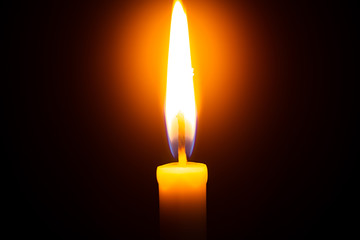 One light candle burning brightly in the black background 