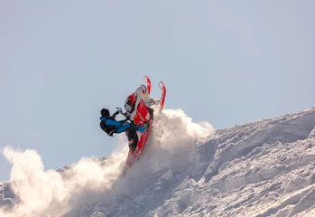 Fotobehang snowmobilers sports riding. Winter extreme ski-doo. an elite snowmobiler is testing a new model of mountain snowmobile, the prototype of 2021. bright snowmobile and suit. rider makes a turn and jump © Wlad Go