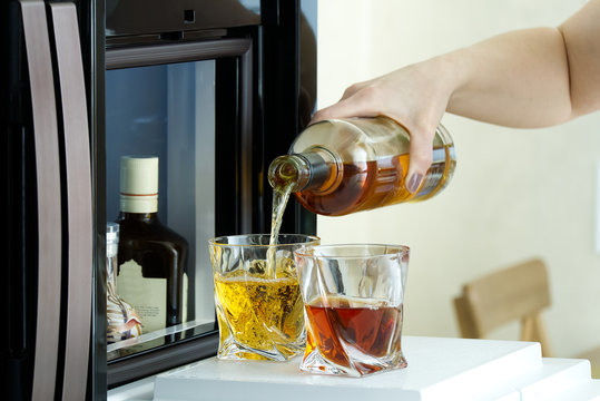 Open Hatch Of A Mini Bar In A Modern Refrigerator. Home Mini Bar In The Fridge. The Owner Pours Guests Alcoholic Drinks, Whiskey, Cognac In Glasses