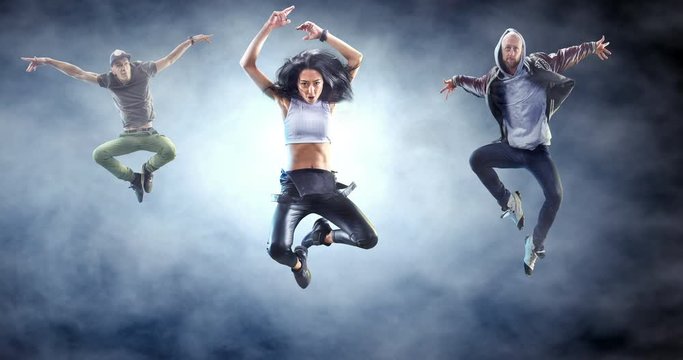 Group of street dancers in a jump with fog on a backgroung.