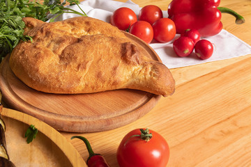 fresh Georgian bread with tomatoes on a wooden cutting board . Georgian cuisine flour products on the background of fresh vegetables. Food background