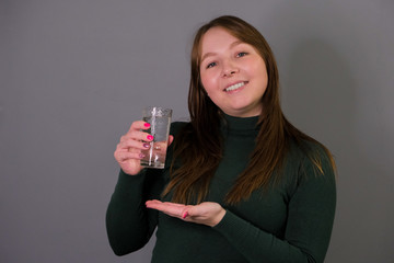 portrait of attractive russian smiling woman isolated on grey studio shot drinking water. photography about the benefits of drinking water