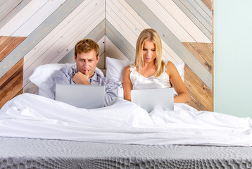 Man and woman look at computer in the bedroom