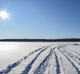 Obraz premium Most beautiful winter landscape. Snowy road. Bright sun over the winter lake. Place for text.