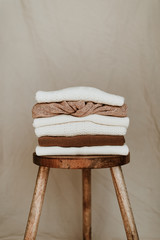 Women fashion composition. Warm winter female woollen knitted sweaters, pullovers stack on a wooden...
