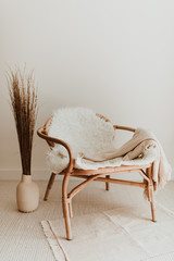 Home interior mockup with wicker rattan armchair, soft beige blanket, white fur and vase with...