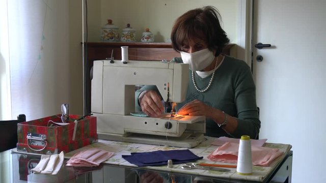 Italy , Milan - Old lady 70 years old sews homemade masks with a sewing machine during n-covid 19 Coronavirus - quarantine at home and lifestyle , seamstress produced masks  at home