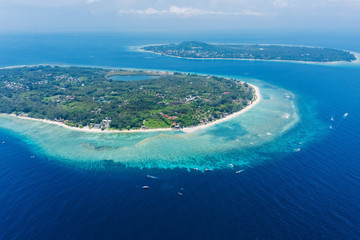 Fototapeta na wymiar Amazing aerial view to Gili islands and Lombok. Unforgettable experience during vacations holidays. Blue sky and lagoon water. Clouds on the horizon. Meno and Trawangan.