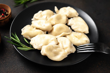 Dumplings or dumplings with cheese in a black plate on a stone background