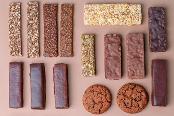 Different Energy protein bars and oatmeal bars on light brown chocolate background. Set of energy, sport, breakfast and protein bars. Copy space. Flat lay