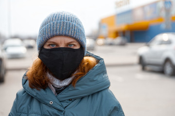 Portrait of woman in city street wearing face mask. Blurred background.