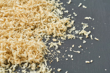 Scattered wooden sawdust on dark concrete surface in carpentry workshop