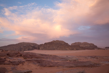 Purple sunset in the Wadi Rum desert. The blue sky is covered with pink clouds. View from the cliff