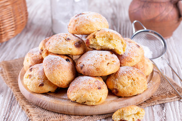 Homemade cottage cheese buns with raisins and icing sugar on a white table