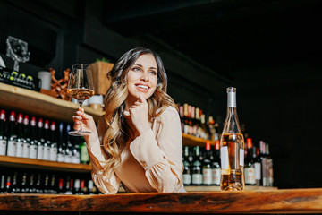Experienced elegant sommelier woman tastes wine in restaurant. Checking taste, colour, sediments of...